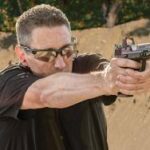 a middle aged person practicing shooting with pistol manufactured by Gretta gun works in shooting ground