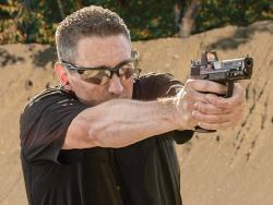 a middle aged person practicing shooting with pistol manufactured by Gretta gun works in shooting ground